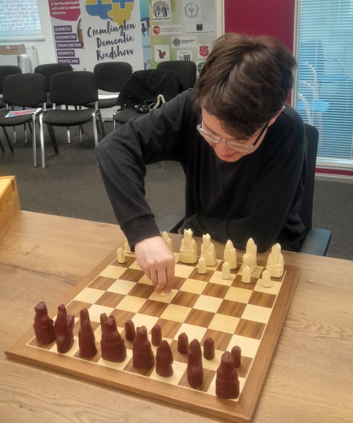 Club member playing with an Isle of Lewis style chess set at a club night